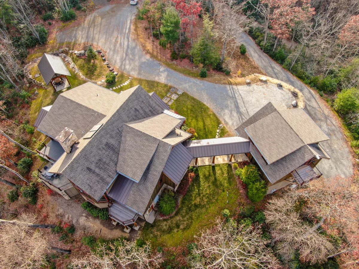A sweeping view of the property, highlighting the main house, circular driveway, connecting pathways, and lush greenery surrounding the lodge. The image captures the expansive outdoor space, perfect for seasonal activities and gatherings, and illustrates the lodge’s private, serene setting.
