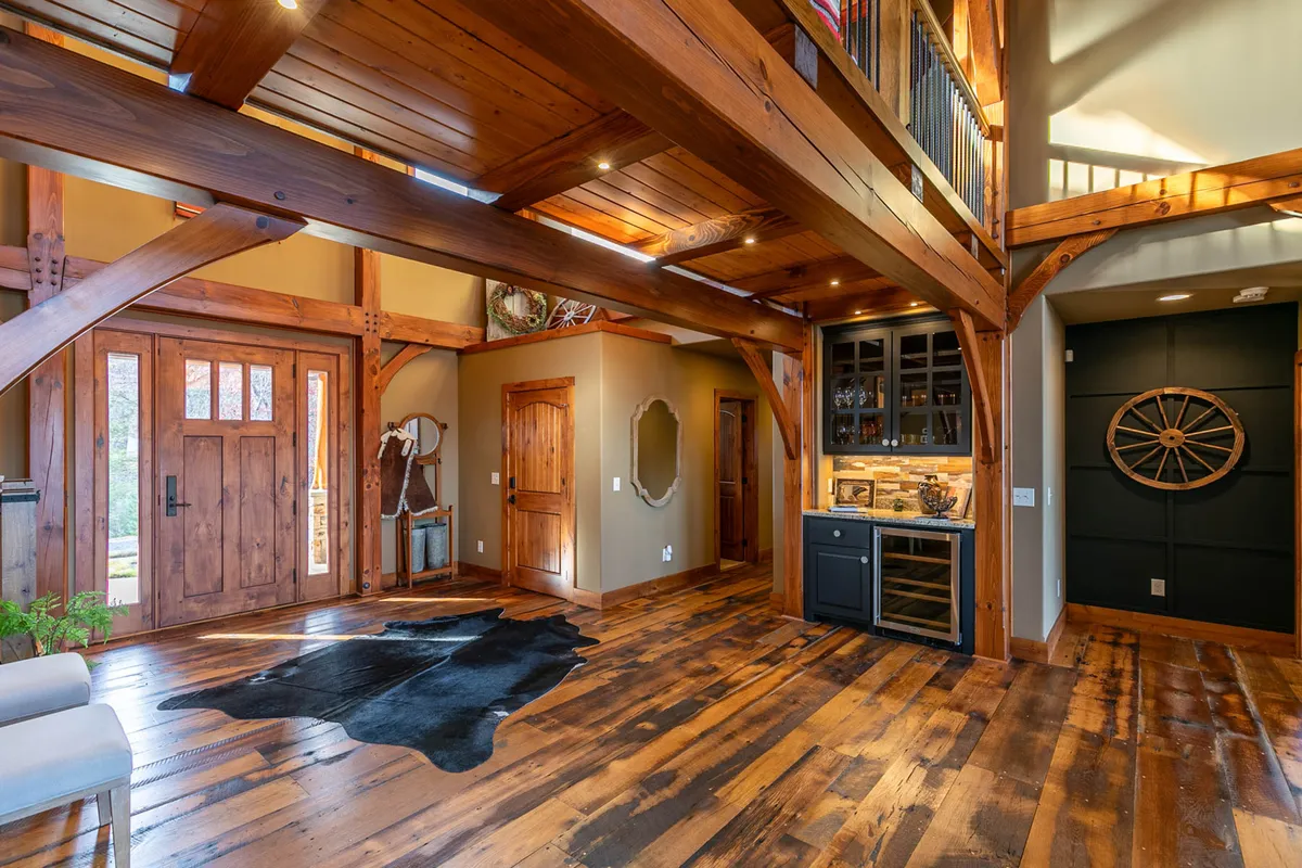 A stylish entryway featuring wooden beams, double doors, a bar area, and a cozy cowhide rug. The space feels secure and welcoming, ideal for receiving guests and starting memorable experiences inside the lodge.