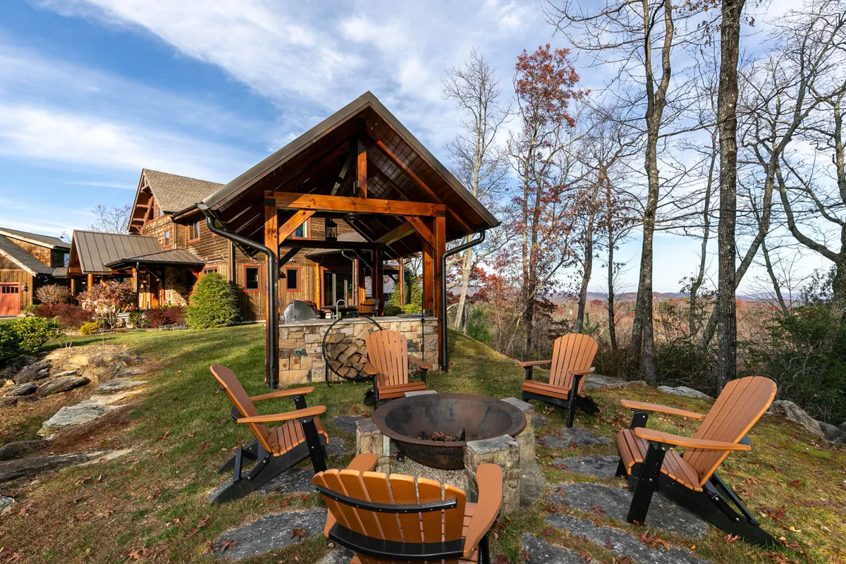 A classic fire pit area surrounded by sturdy wooden chairs, set within a natural landscape. The stone fire pit serves as a central gathering place, ideal for storytelling, stargazing, and enjoying evenings outdoors with friends and family.