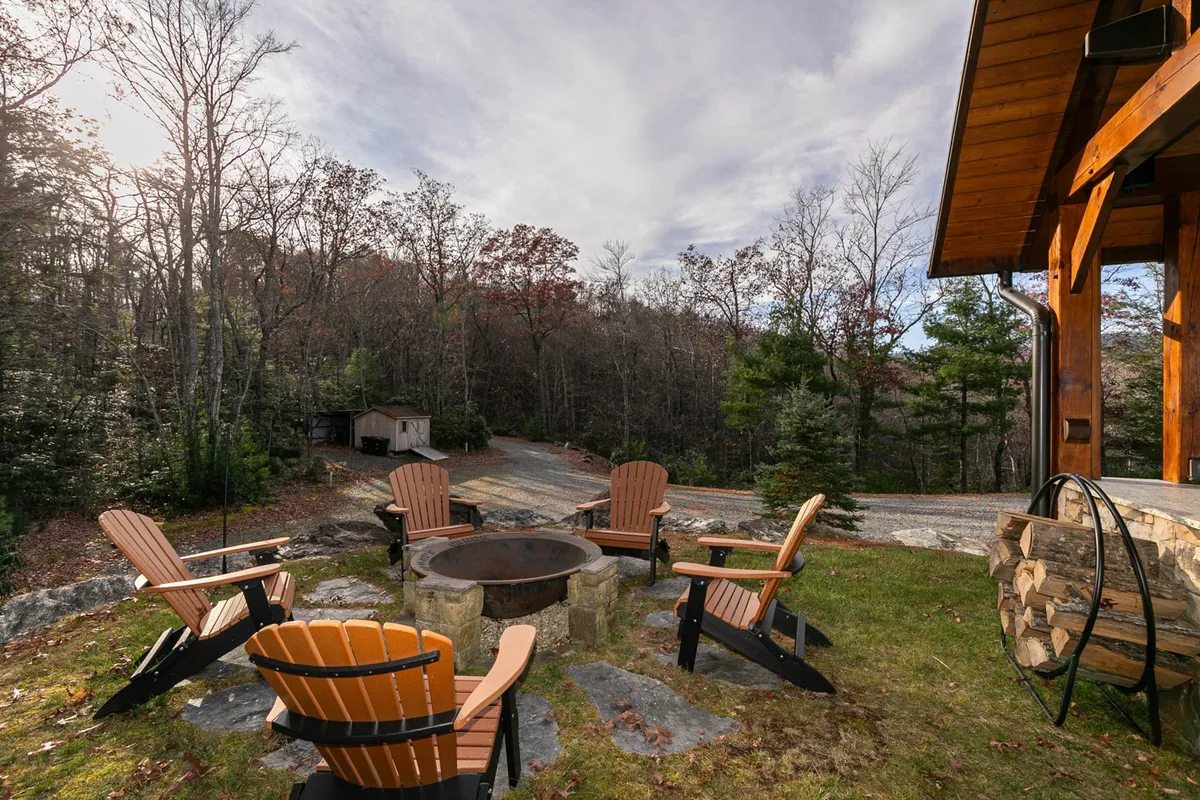A cozy outdoor fire pit surrounded by Adirondack chairs and trees, with wood logs ready for a fire. This inviting scene encourages storytelling, s'mores, and stargazing under the night sky, making it ideal for family bonding moments.